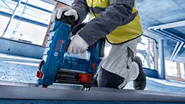 En hantverkare använder en blå Bosch batteridriven spikpistol på en byggarbetsplats.