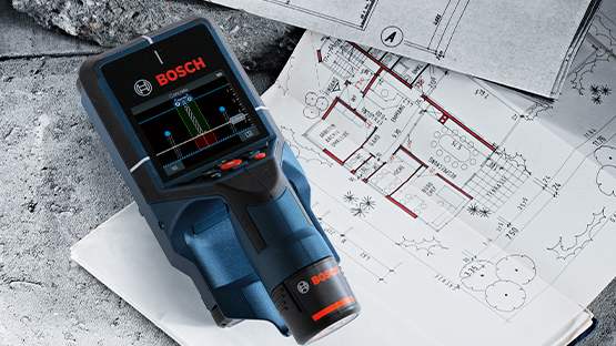 Um medidor de distância a laser Bosch Professional azul está sobre um plano branco com desenhos de construção.