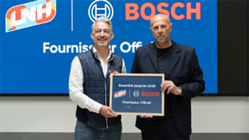 Deux hommes tiennent une pancarte avec le logo Bosch devant un écran.