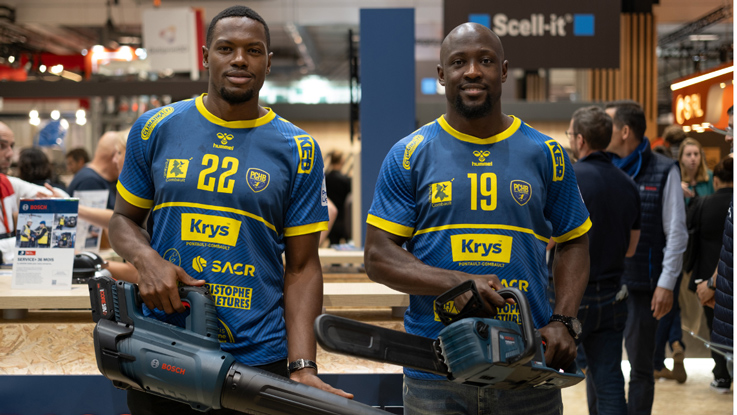 Deux hommes en maillots bleus tiennent des outils Bosch lors d'un salon.