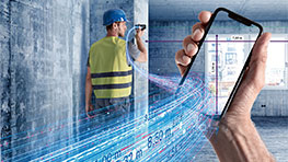 A worker with a helmet measures a wall with a smartphone.