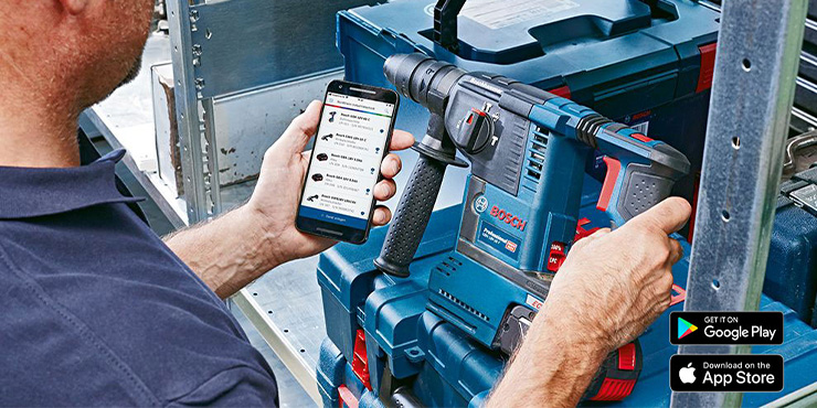 Mężczyzna trzyma narzędzie Bosch Professional i telefon w warsztacie.