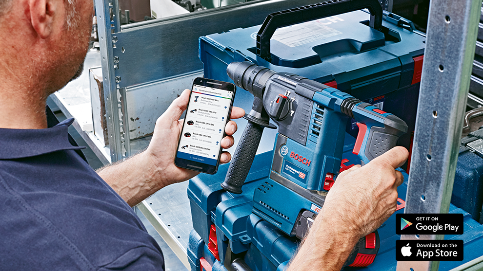 Un homme tient un perforateur Bosch Professional et un smartphone dans un atelier.