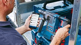 En man använder ett Bosch Professional verktyg och en smartphone.