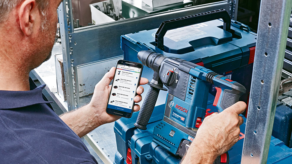 Mees hoiab sinist Bosch Professional puure ja vaatab oma nutitelefoni.