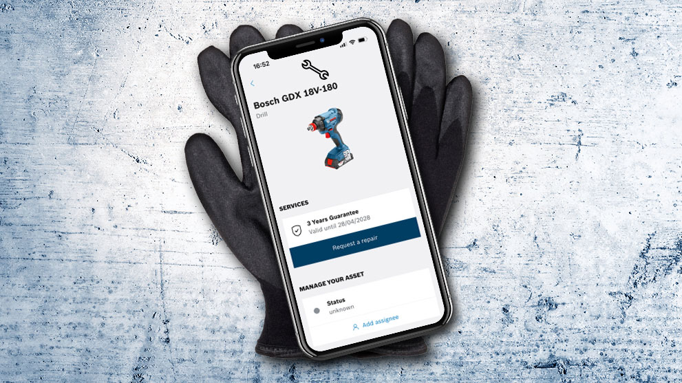 Een smartphone toont Bosch GDX 18V-180 op een grijze achtergrond naast zwarte handschoenen.