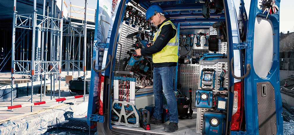 En hantverkare i en blå skyddsväst arbetar i en blå skåpbil.