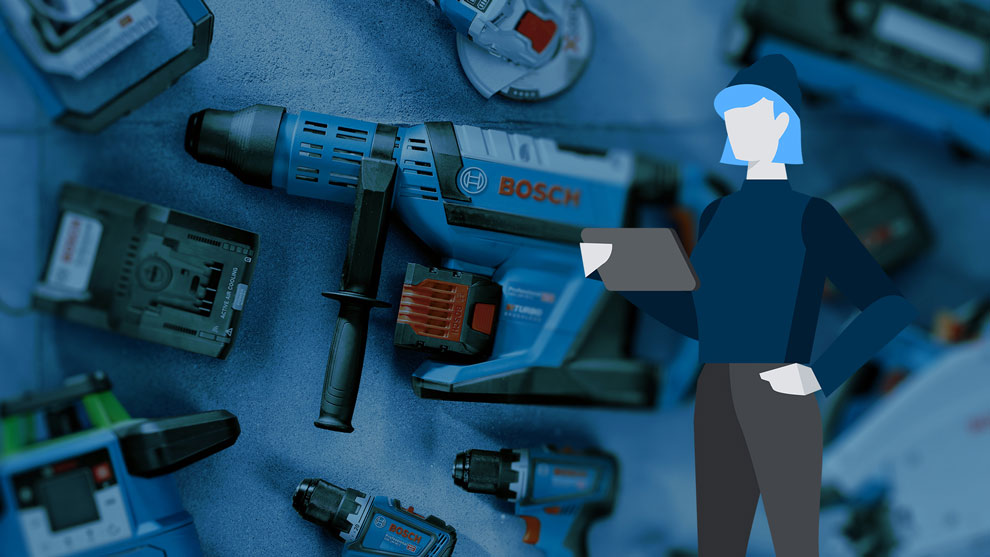 En person håller en surfplatta bredvid Bosch-verktyg på ett bord.