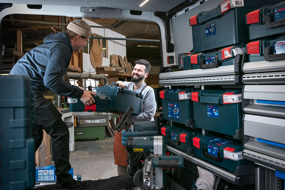 Kaksi miestä nostaa Bosch-työkalupakkia pakettiautoon.