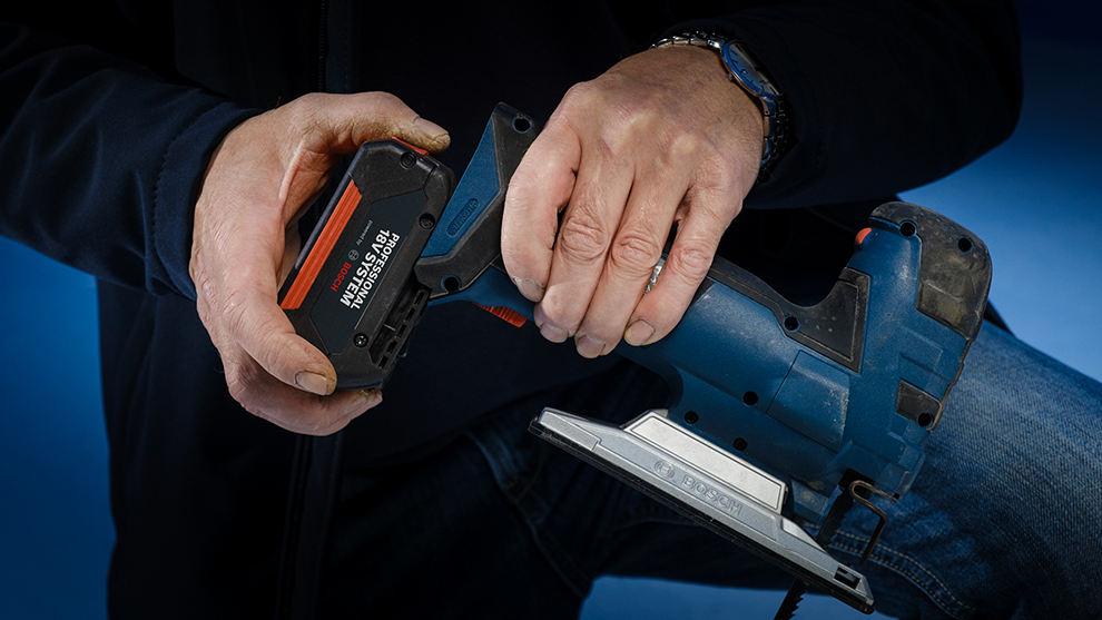 Käed vahetavad sinise Bosch Professional tööriista akut.