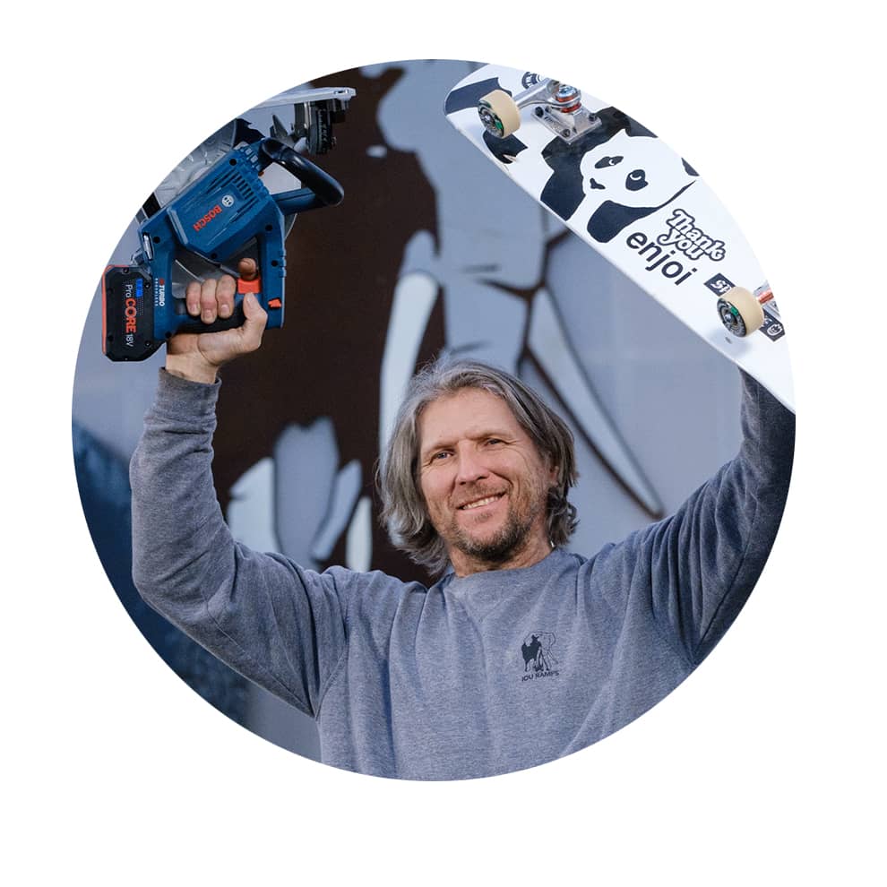 En man håller en blå Bosch Professional batteridriven spikpistol och en skateboard.