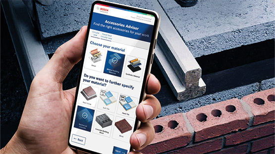 Een hand houdt een smartphone met een app voor materiaalkeuze. Op de achtergrond zijn bouwmaterialen te zien.