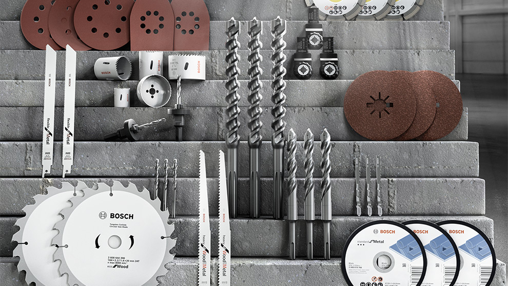 Een verscheidenheid aan gereedschappen en accessoires, waaronder zagen, boren en schuurschijven, op een grijze werkbank.