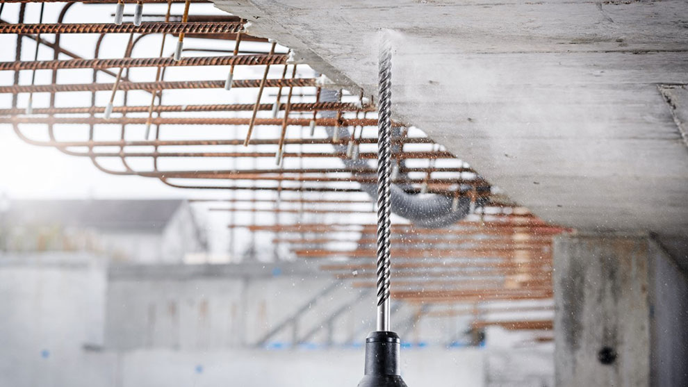 A Bosch Professional drill penetrates concrete with water mist.
