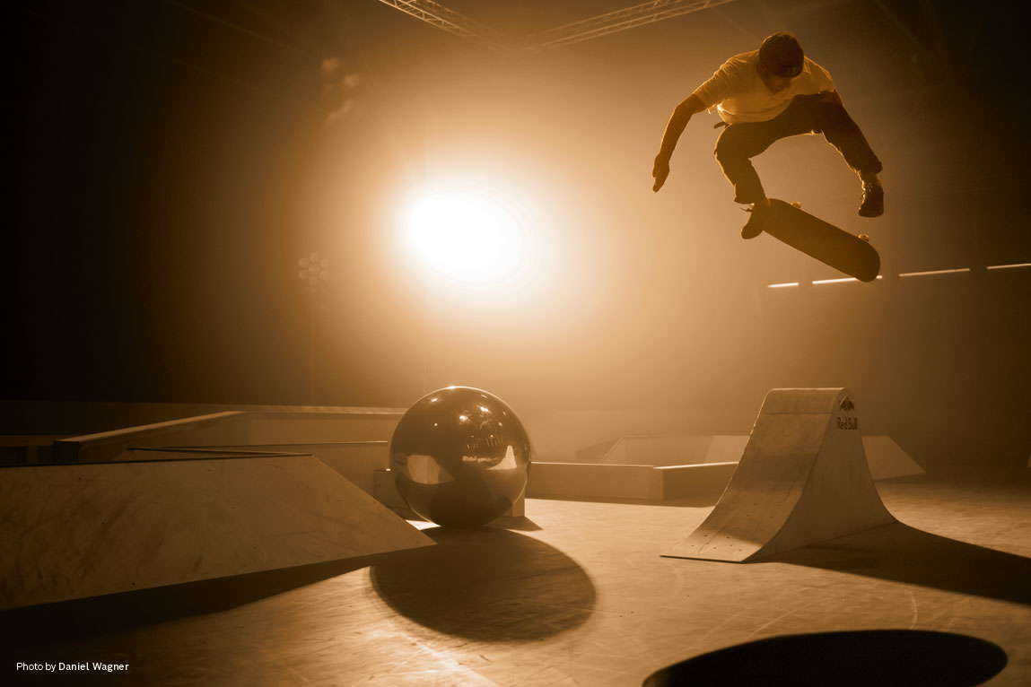 Ένας σκιέρ κάνει άλμα με ένα σκέιτμπορντ πάνω από μια ράμπα σε μια αίθουσα.