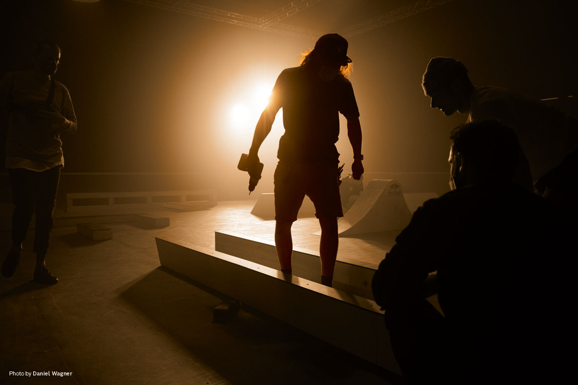 Ένα άτομο στέκεται σε μια ράμπα σκέιτ σε χαμηλό φωτισμό.