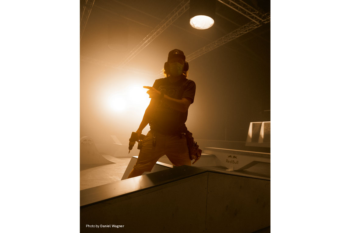 Ένας άντρας με εργαλεία στέκεται σε μια φωτισμένη αίθουσα σκέιτ.