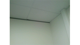 Hoek van een kamer met witte muren en plafond, minimalistisch en helder.