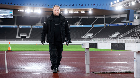 Musta pukeutunut mies kävelee kilparadalla.