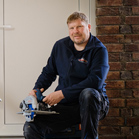 Mann mit Bosch Professional Werkzeug sitzt auf dem Boden vor einer Wand.