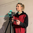 Eine Frau mit blonden Haaren bedient einen grünen Laser auf einem Stativ.