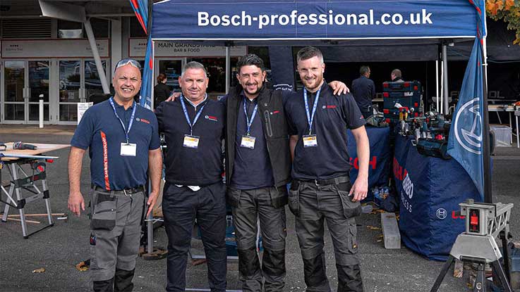 Four men in Bosch Professional T-shirts are standing in front of a tent.