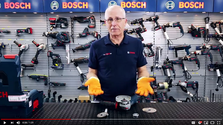 A man with orange protective gloves shows a Bosch angle grinder.