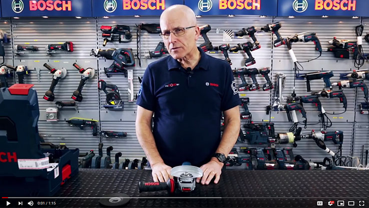 A man presents a Bosch Professional angle grinder on a table.