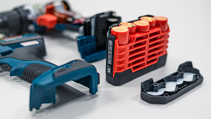 Batterie rouge Bosch Professional à côté de la poignée d'outil bleue et des pièces.