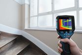 Person uses thermal camera to scan temperature changes near a window.