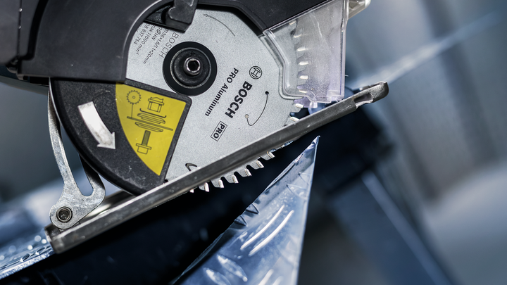 Circular saw blade cutting through a sheet of metal.