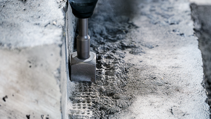 Demolition hammer chiseling concrete surface.