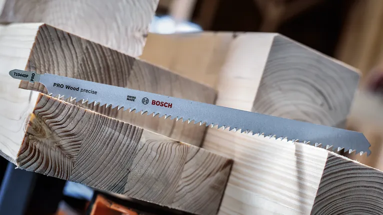 Saw blade positioned on stacked wooden beams.