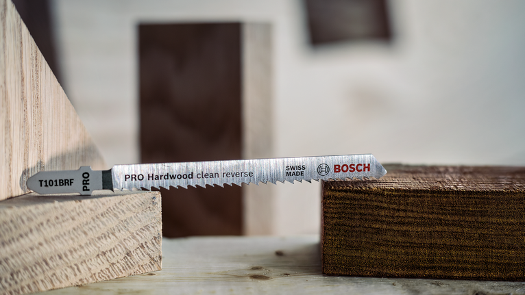 Jigsaw blade positioned between wooden blocks on a workbench.