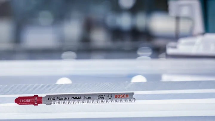 Jigsaw blade resting on a clear plastic sheet in a workshop setting.