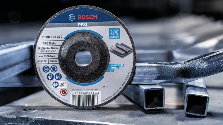 Cutting disc resting on stacked metal square tubes in an industrial setting.