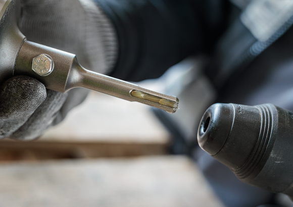 Person wearing safety equipment inserting a drill bit into a rotary hammer.