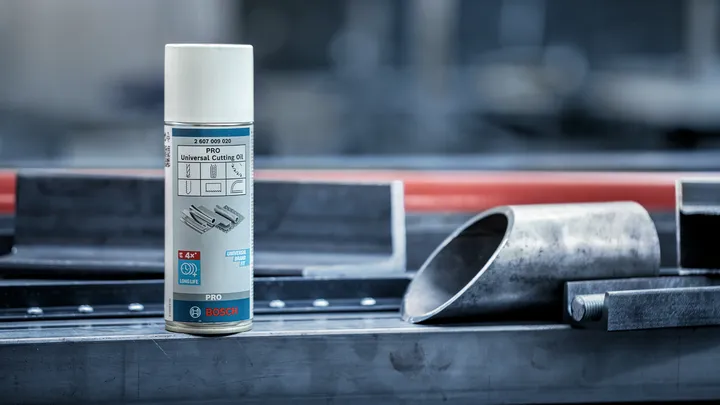 Cutting oil spray can placed on a metal workbench beside steel pipes.