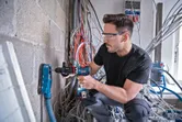 Una persona que usa equipo de seguridad perfora una pared de hormigón con extracción de polvo.