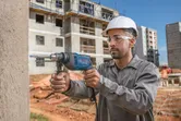 Una persona que usa equipo de seguridad perfora una pared de hormigón en un sitio de construcción.