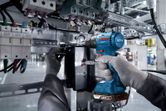 Una persona que usa equipo de seguridad utiliza un taladro inalámbrico en un panel eléctrico.