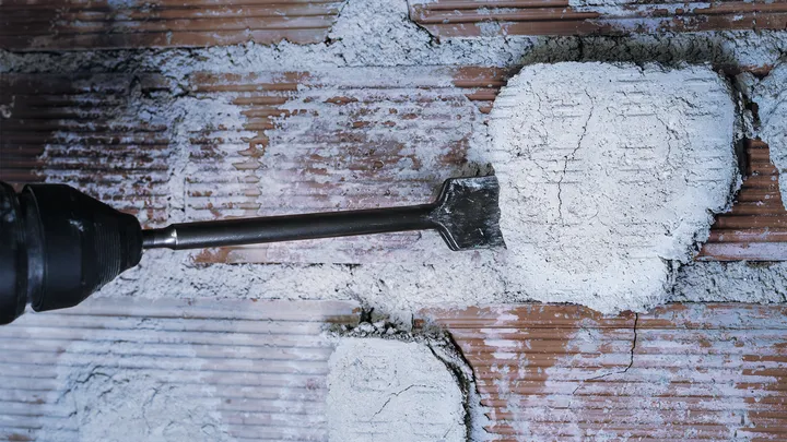 Broca de cincel para quitar yeso de una pared de ladrillos.