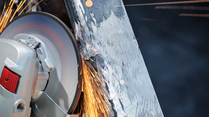 La rueda de corte genera chispas al cortar una viga de metal.