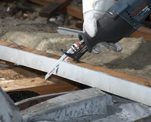 Una persona que usa equipo de seguridad corta una viga de madera utilizando una sierra alternativa.