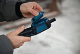 Una persona inserta una batería en una herramienta portátil de color azul.