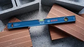 Un nivel de burbuja azul descansa sobre ladrillos apilados y bloques de hormigón.