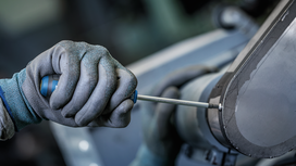 Una persona que lleva puesto un equipo de seguridad aprieta un tornillo en una máquina industrial.