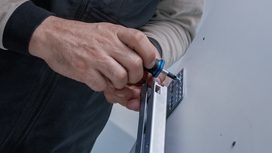 Una persona utiliza un destornillador para fijar un soporte metálico a la pared.