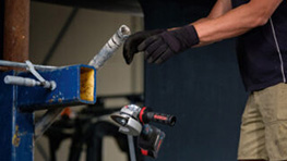 Un trabajador con guantes sostiene un destornillador Bosch cerca de una máquina de trabajo.