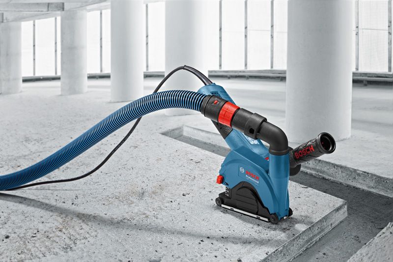 Wall chaser with dust extraction hose is cutting a groove in a concrete floor.